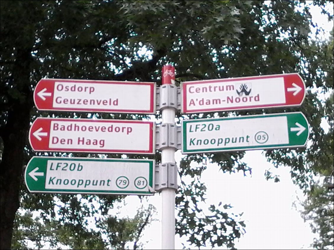 La Hollande, pays du vélo.
Les numéros dans les cercles verts indiquent les croisements des principales pistes cyclables. Les pancartes rouges donnent les directions des villes.
Je suis la voie Lf2 qui relie Bruxelles à Amsterdam. Je roule essentiellement le long de canaux ou à travers des prairies, c'est très champêtre.