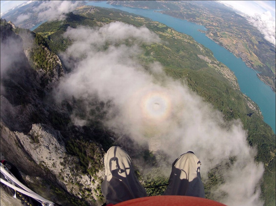Spectre de Brocken et gloire au cours d'un vol en parapente depuis le sommet du Morgon. Au premier plan, les jambes du pilote.
Photo : Carnets d'Aventures